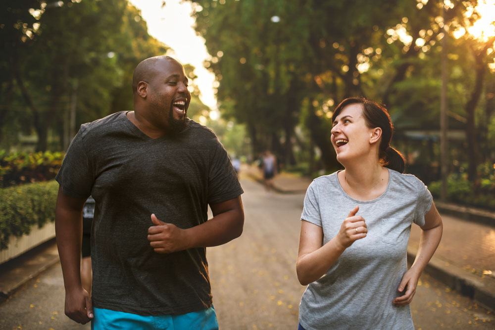 man and woman walking in park with trees in background