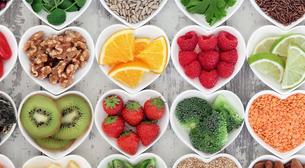 A colorful assortment of fruits and vegetables beautifully arranged in heart-shaped bowls, showcasing vibrant natural hues.
