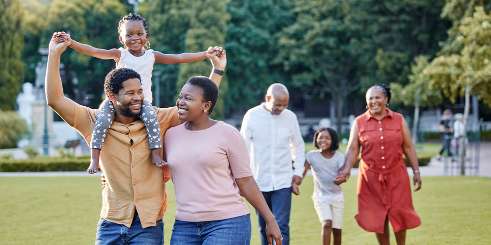 A happy family of four strolls together through a sunny park, enjoying their time outdoors.