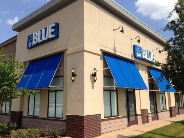 Front of store front with blue awning and blue cross logo