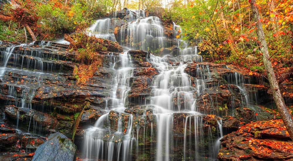 Waterfall over rocks with vibrant trees and leaves