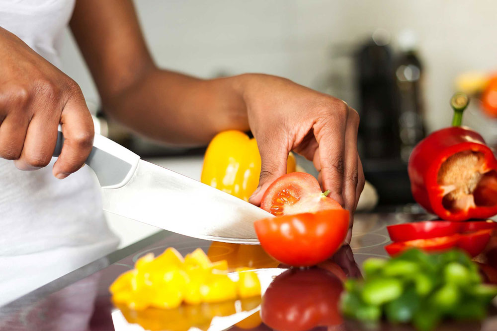 woman chops fresh vegetables with knife