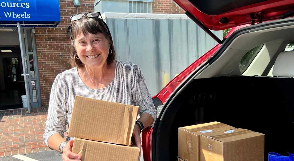 Woman holding boxes with trunk open