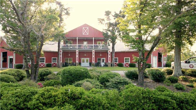 Image of red barn building with trees and bushes
