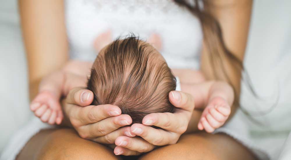 mothers hands holding new baby