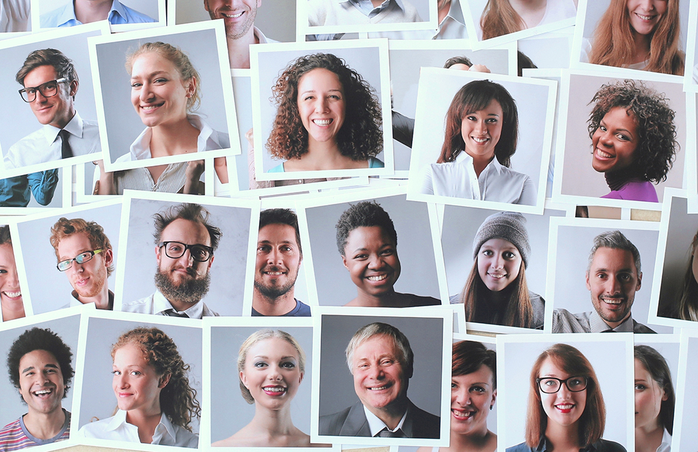 Multiple headshots of people of different ethnicities are spread out on a surface