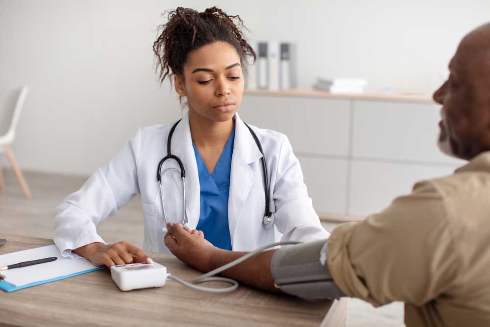 Nurse with stethoscope checking blood pressure of man 