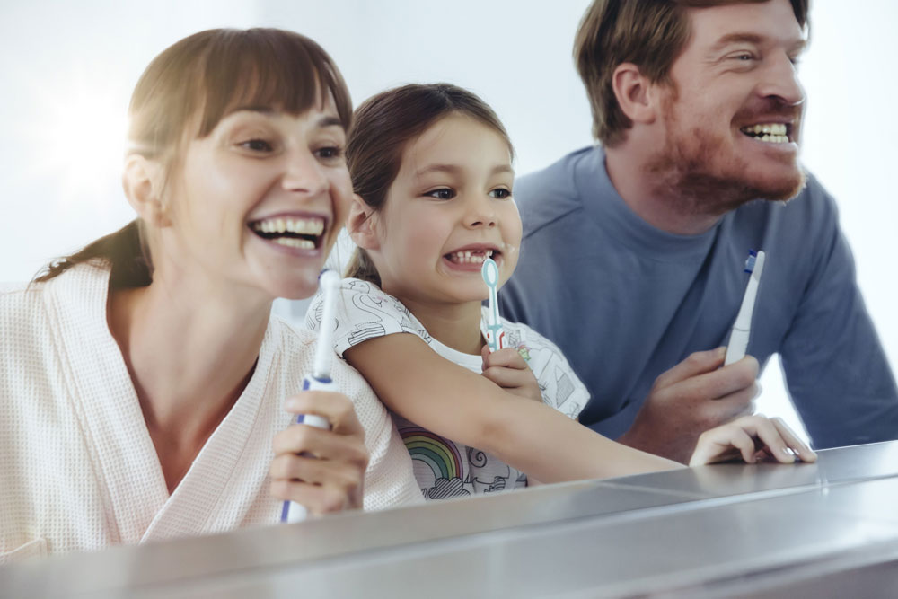 Man woman and child brushing teeth in mirror