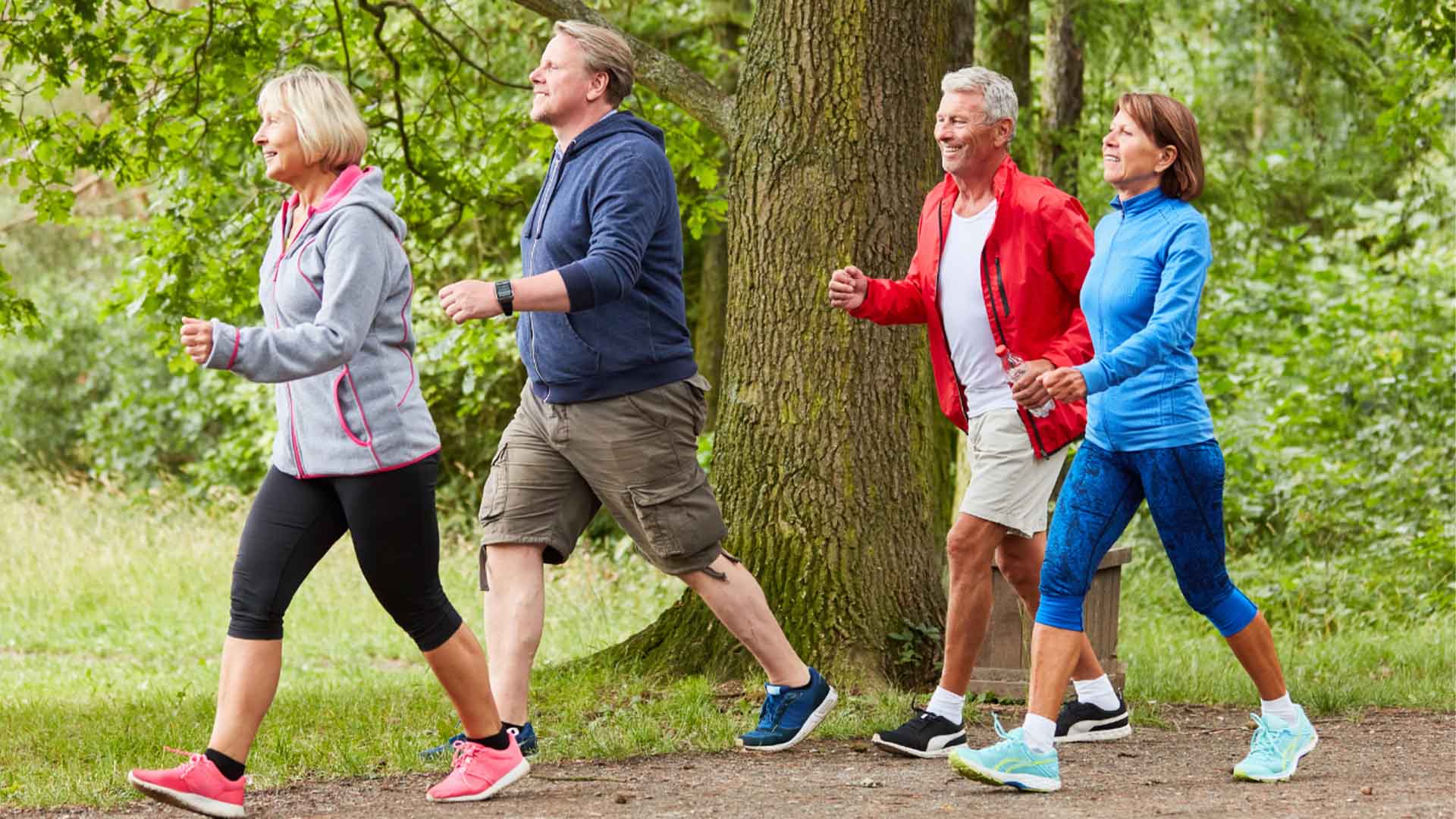 A group of diverse individuals jogging together on a sunny day in a green park.
